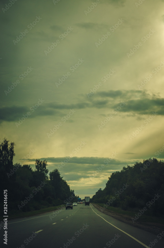 Long way to the horizon on the cloudy evening with road and cars. Vintage toned background
