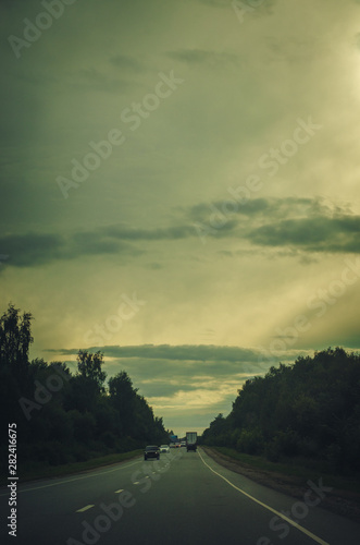 Long way to the horizon on the cloudy evening with road and cars. Vintage toned background
