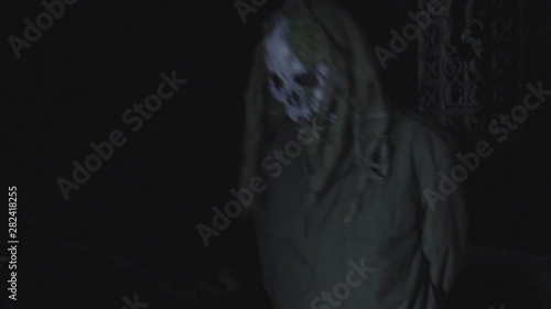 Unrecognizable man with scary halloween mask at night in the dark. Black magic ritual or scary halloween party performance