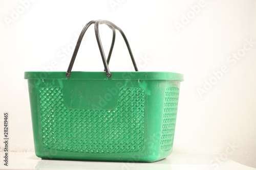 Green plastic shopping basket with black handles.