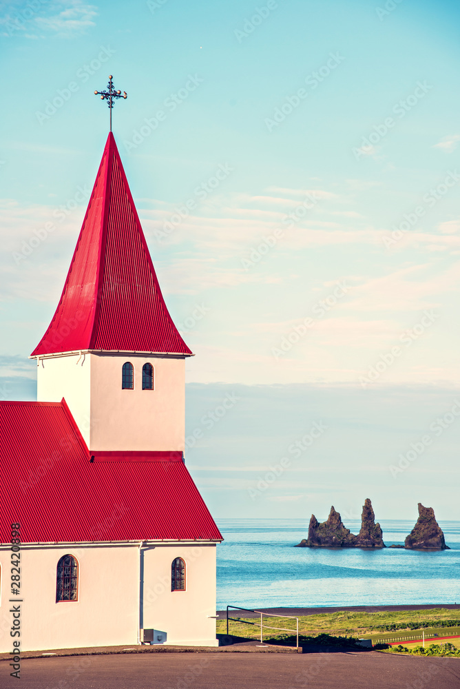 The famous Vik church (Vikurkirkja) on the background of the sea and the fingers of the troll in Iceland. place of pilgrimage. Impressive landscape. Exotic countries. Amazing places.