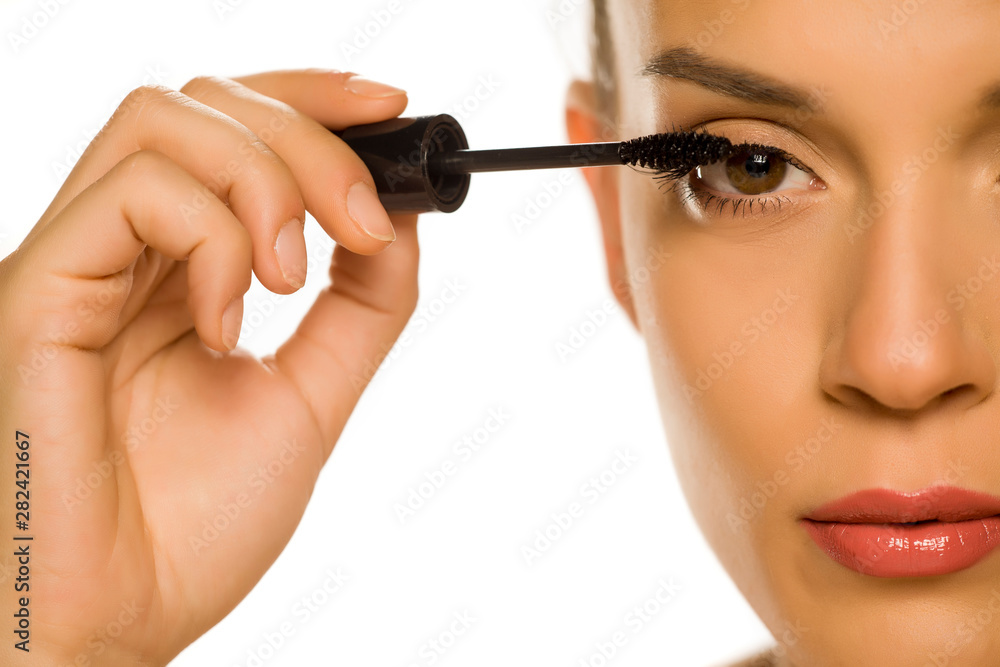 woman applying mascara on her eyelashes