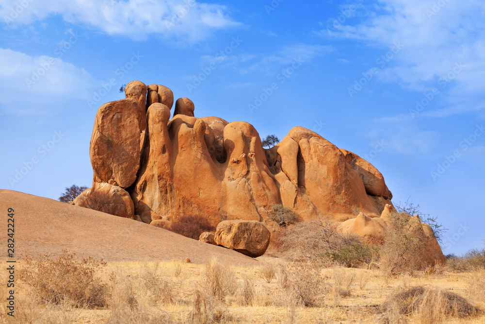 Red bald granite peaks on blue sky background, ancient geological formations, orange stones, natural yellow rocks, Erongo mountains, Damaraland, Naukluft national park, Namib Desert, Namibia, Africa Red bald granite peaks on blue sky background, ancient geological formations, orange stones, natural yellow rocks, Erongo mountains, Damaraland, Naukluft national park, Namib Desert, Namibia, Africa