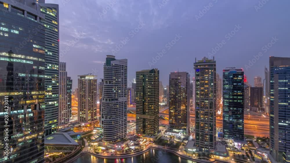 Residential and office buildings in Jumeirah lake towers district day to night transition timelapse in Dubai. Aerial panoramic view from above with modern skyscrapers Residential and office buildings in Jumeirah lake towers district day to night transition timelapse in Dubai. Aerial panoramic view from above with modern skyscrapers