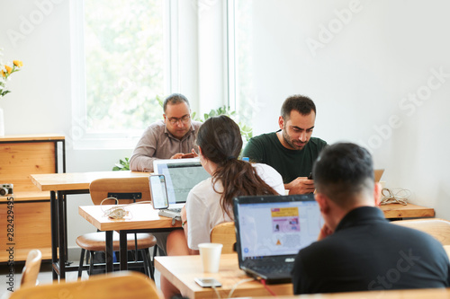 Group of IT manager sitting at their workplaces and using laptop computers in work at the office