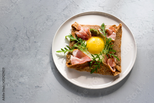 Galette bretonne  with fried eggs, arugula and bacon.
