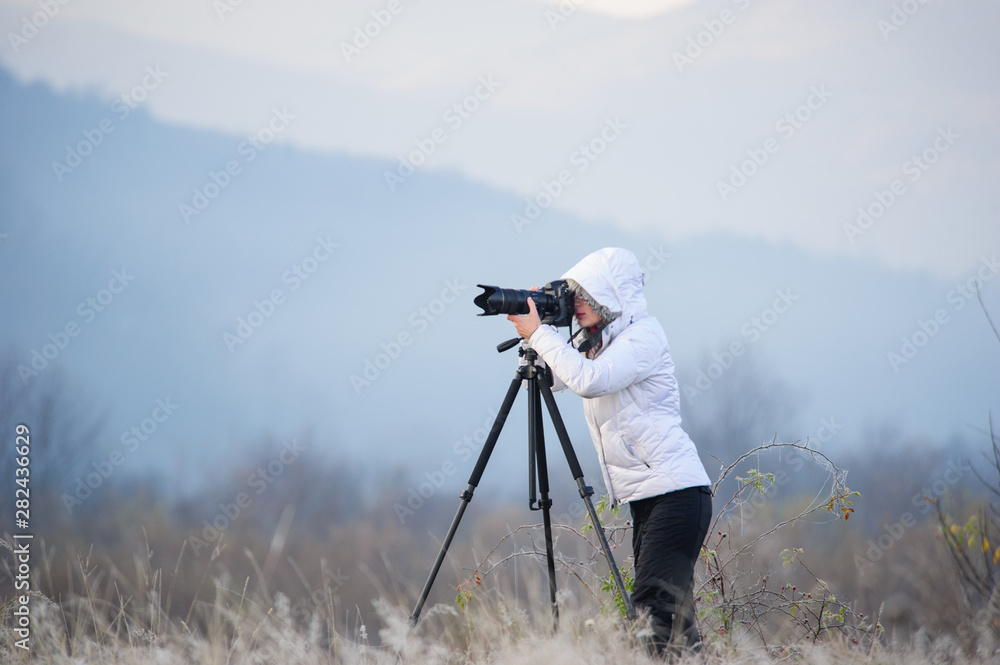 photographer with camera and tripod outdoor taking landscape picture
