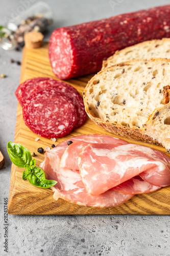 Traditional artisan bread with seeds and pork sausage and salami served on a wooden cutting board. Open sandwich with pork sausage.