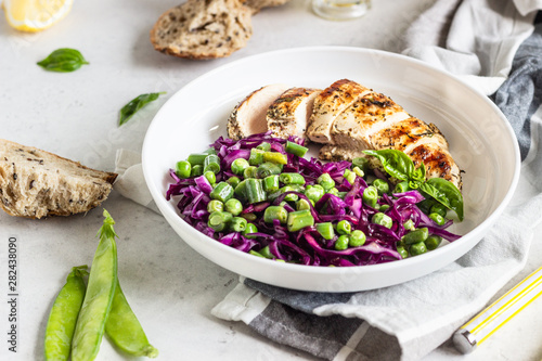Grilled chicken, red cabbage, green peas and beans on light background. Delicious balanced food concept. Healthy lunch or dinner salad.