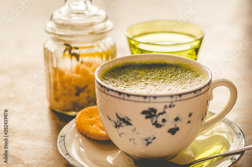 green tea matcha soy latte in a china cup with brown sugar and a glass of water on the side