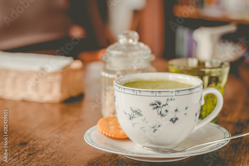 green tea matcha soy latte in a china cup with brown sugar and a glass of water on the side