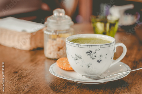 green tea matcha soy latte in a china cup with brown sugar and a glass of water on the side