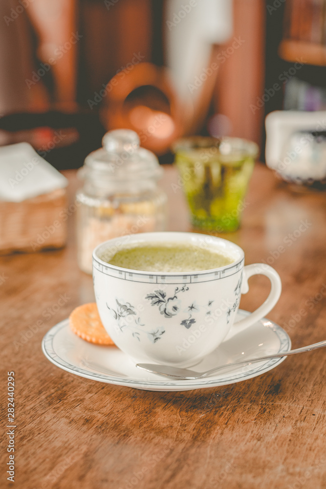 green tea matcha soy latte in a china cup with brown sugar and a glass of water on the side green tea matcha soy latte in a china cup with brown sugar and a glass of water on the side
