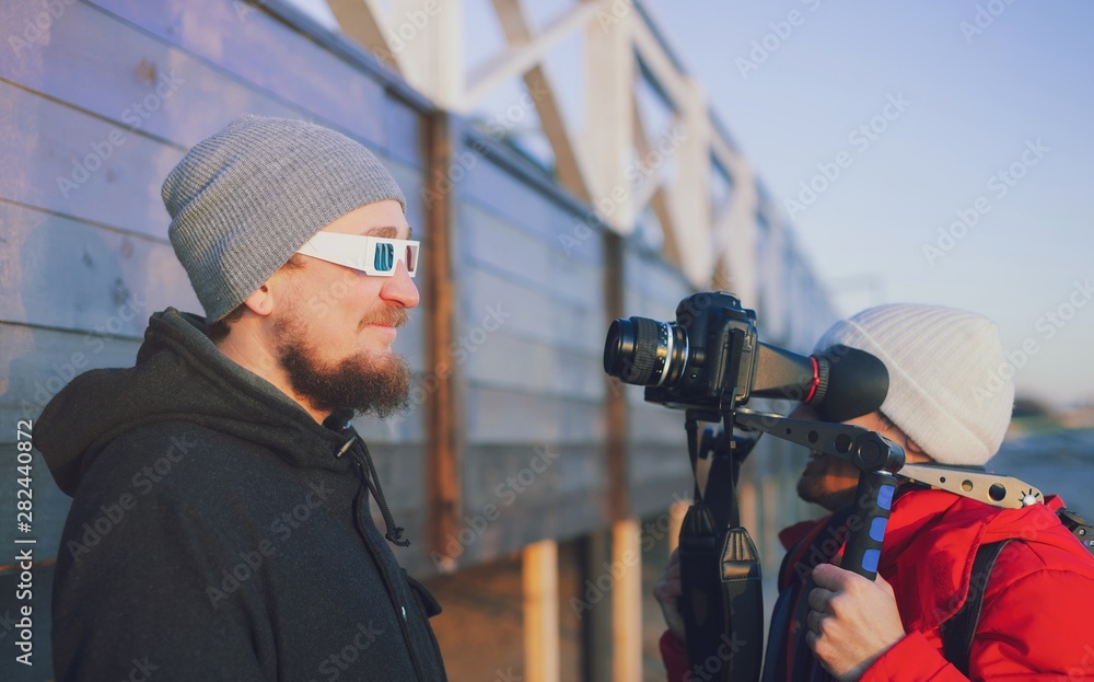 Actor in camera on outdoor winter location. Videographer with gimball video dslr Young professional vlogger videographer shooting outdoor on modern camera. Filming interview vlog behind the scene. Actor in camera on outdoor winter location. Videographer with gimball video dslr Young professional vlogger videographer shooting outdoor on modern camera. Filming interview vlog behind the scene.