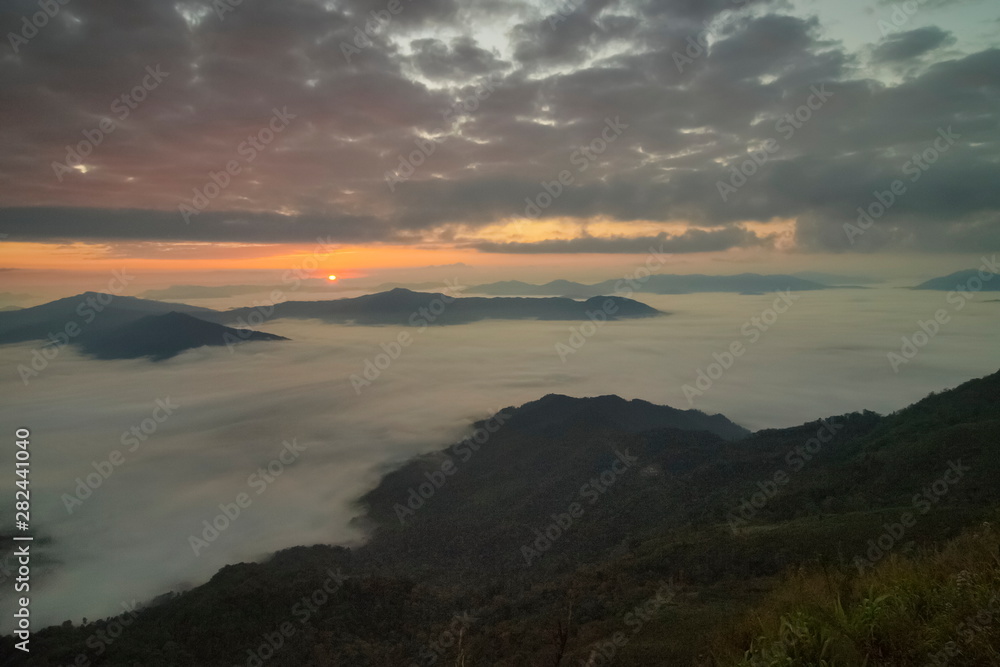 Mountain view morning of top hill around with sea of mist in valley with orange sun light and cloudy sky background, sunrise at Pha Tang, Chiang Rai, northern of Thailand.