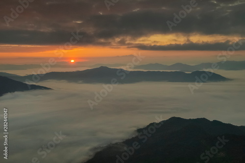 Mountain view morning of top hill around with sea of mist in valley with orange sun light and cloudy sky background, sunrise at Pha Tang, Chiang Rai, northern of Thailand.