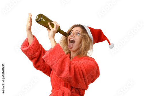 funny girl in a robe and Santa's hat, drinking alcohol from a bottle. Open mouth. Alcoholic. New Year. Isolated on white background