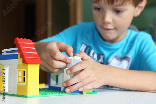 Junge baut mit Bausteinen ein Haus photo