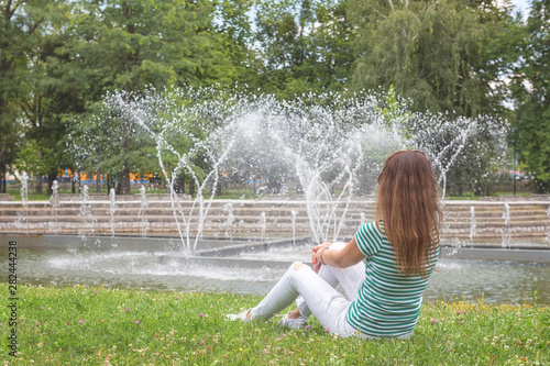 People, travel and summer holidays concept. Young woman in the beautiful green garden enjoy the view of the fountain. Mestsky or City park of Kosice, Slovakia (Slovensko) photo