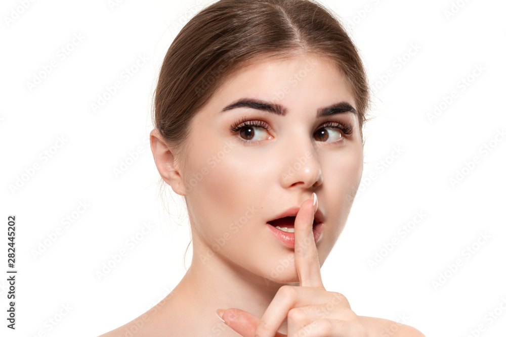 Close-up portrait of a beautiful young girl holding finger near her mouth expressing idea of secret isolated over white background. Close-up portrait of a beautiful young girl holding finger near her mouth expressing idea of secret isolated over white background.