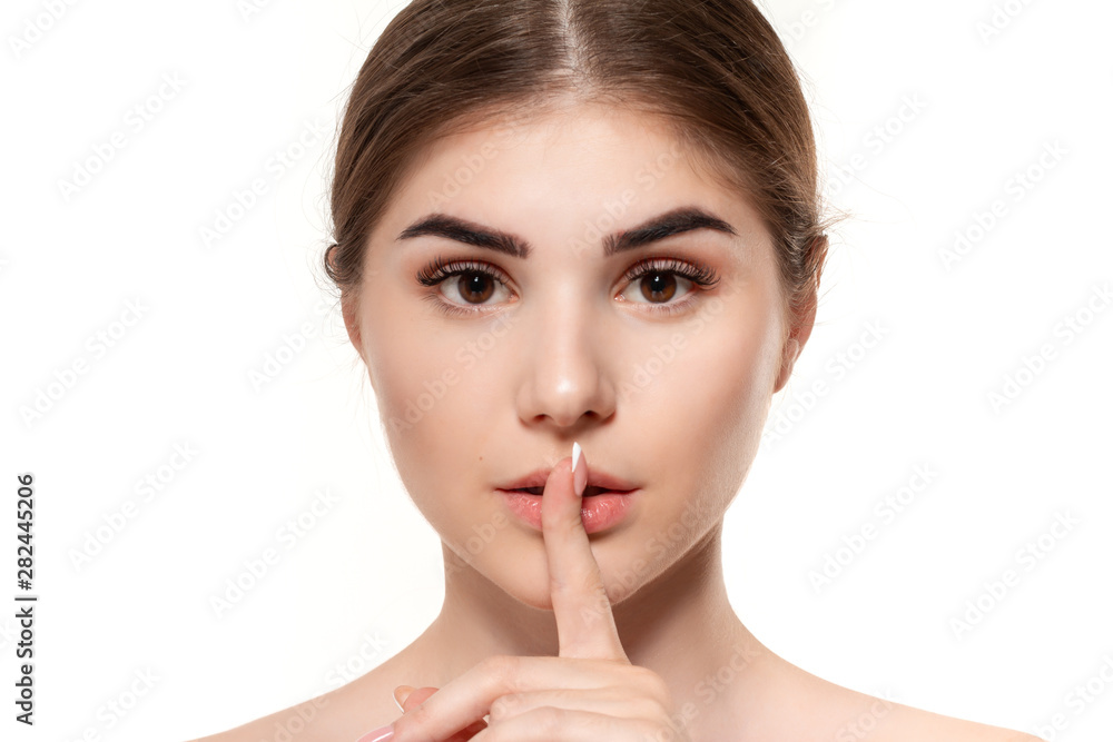 Close-up portrait of a beautiful young girl holding finger near her mouth expressing idea of secret isolated over white background. Close-up portrait of a beautiful young girl holding finger near her mouth expressing idea of secret isolated over white background.