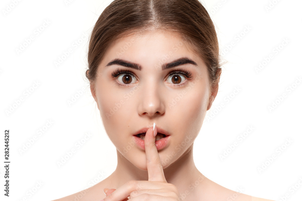 Close-up portrait of a beautiful young girl holding finger near her mouth expressing idea of secret isolated over white background. Close-up portrait of a beautiful young girl holding finger near her mouth expressing idea of secret isolated over white background.