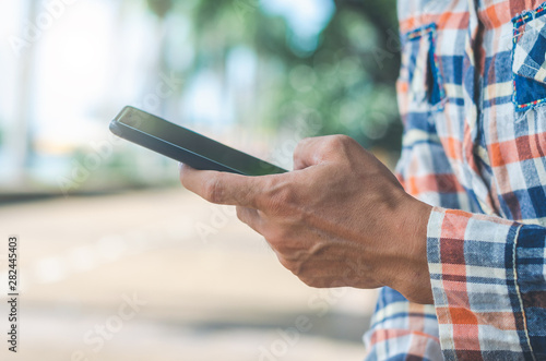 close up handsome man using hand typing mobile phones and touch screen working search with app devices outdoor in city with sunrise and building background. 5G technology connecting the world.