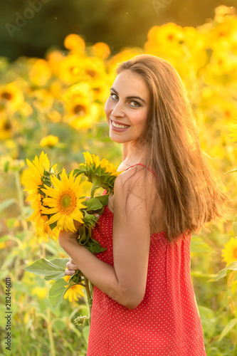 Portrait of young woman in the field with sunflowers