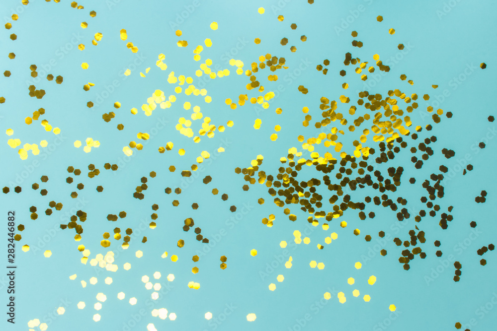 Turquoise festive background with golden confetti. The surface is strewn with shiny sparkles. Flat lay, top view. Turquoise festive background with golden confetti. The surface is strewn with shiny sparkles. Flat lay, top view.