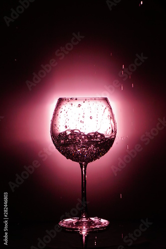 Pouring water into glass , black background and red light