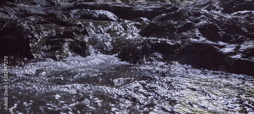 Creek river water flowing on stones
