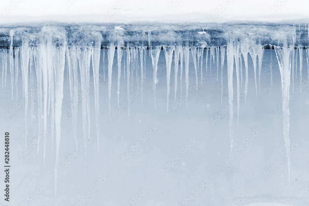 Icicles hang on the roof over light blue wall - obrazy, fototapety, plakaty 