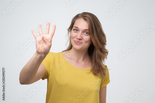 Pretty caucasian young woman holding up four fingers photo