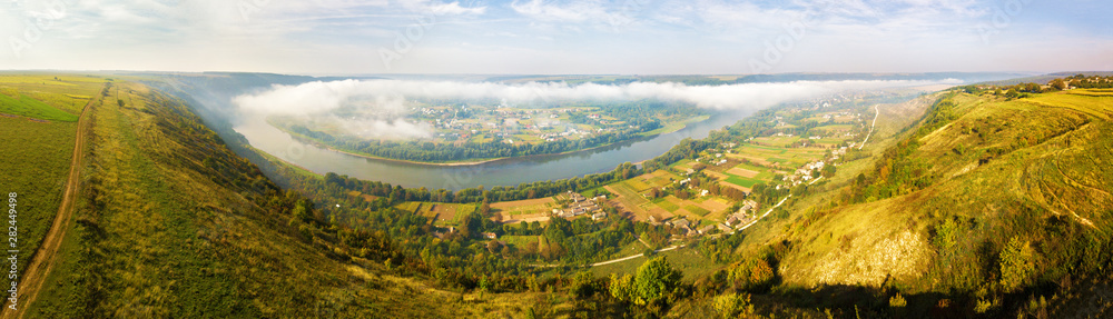 Beautiful panorama of river canyon. Morning fog over the village in valley