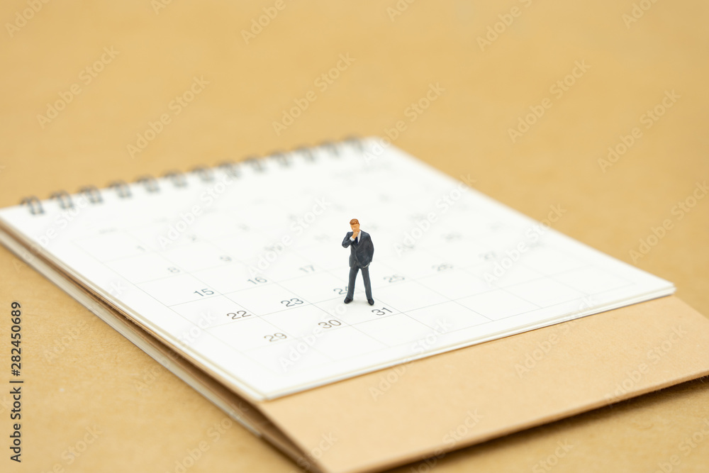 Miniature people businessmen standing on white calendar using as background business concept and finance concept with copy space for your text or design. Miniature people businessmen standing on white calendar using as background business concept and finance concept with copy space for your text or design.