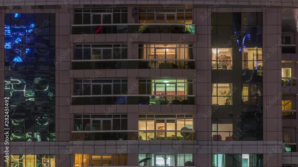 Night view of exterior apartment building timelapse. High rise skyscraper with blinking lights in windows with people moving inside. Pan up Night view of exterior apartment building timelapse. High rise skyscraper with blinking lights in windows with people moving inside. Pan up
