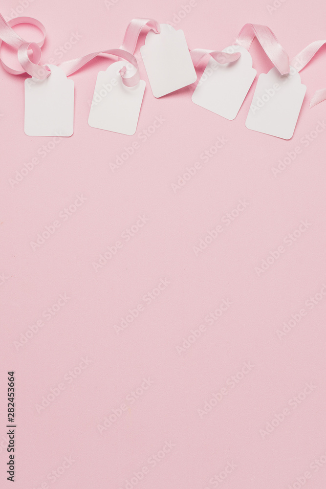 White tags and pink ribbon at the top of the background with space for text