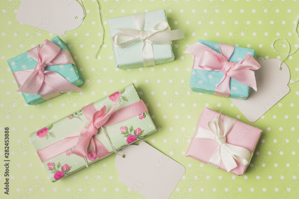 Gift boxed wrapped in design paper with white tag over green polka dot surface Gift boxed wrapped in design paper with white tag over green polka dot surface