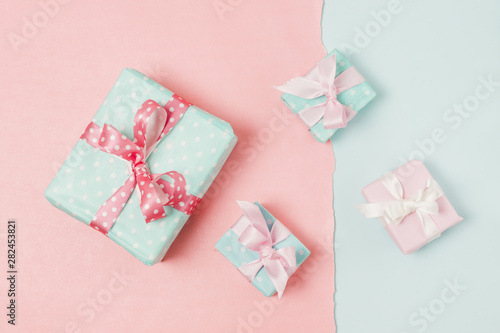 Small and big decorated gift boxed tied with ribbon arrange on peach and blue wallpaper © Freepik