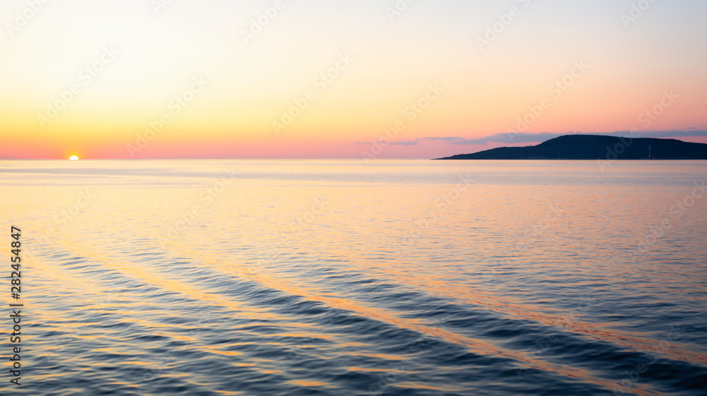 Fototapeta premium Beautiful sunset and gently lappin waves viewed from the deck of a Cruise Ship on the baltic Sea