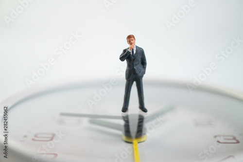 Figure businessmen are thinking And standing on the white watch face by the watch face showing the time. Concept of time management.