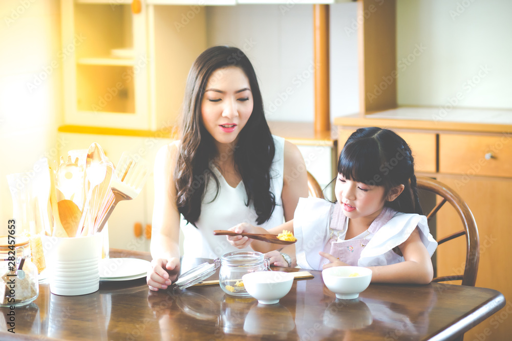 Mother and child daughter Spread butter on bread in the morning. happy family in the kitchen Mother and child daughter Spread butter on bread in the morning. happy family in the kitchen