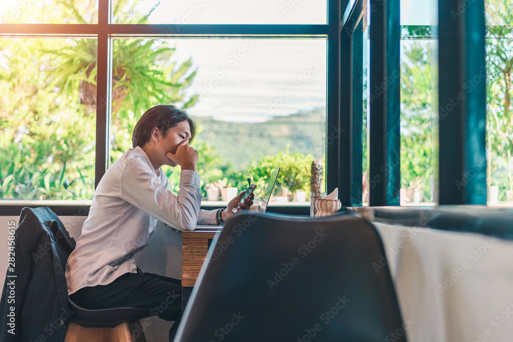Businessmen are thinking,wearing glasses and smiling, as he works on his laptop to get all his business done early in the morning with his cup of coffee Businessmen are thinking,wearing glasses and smiling, as he works on his laptop to get all his business done early in the morning with his cup of coffee