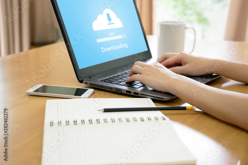 Woman trying to find work with online  to cloud downloading on laptop photo