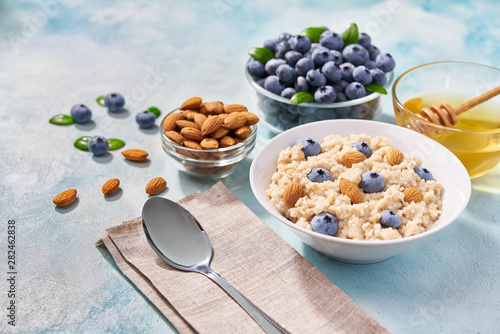 breakfast cereals with blueberries and almond in ceramic bowl on a turquoise background.