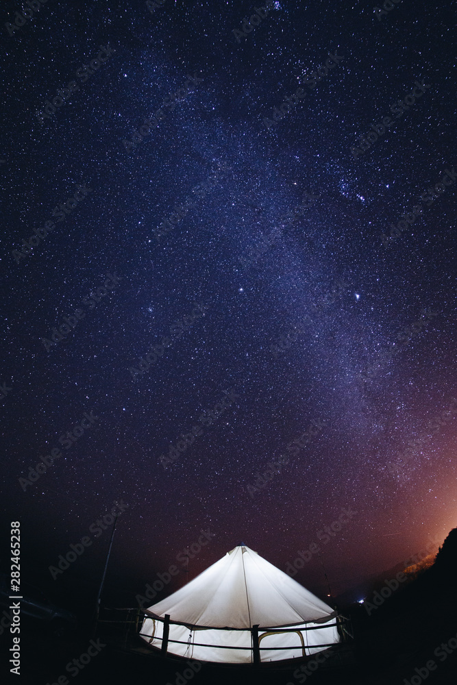 Tent with travelers in landscape night sky stars milky way on mountains background