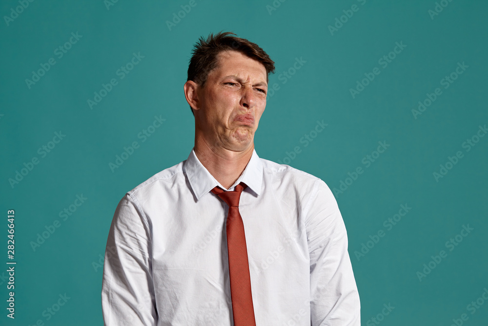 Young man in a classic white shirt and red tie posing over a blue background. Young man in a classic white shirt and red tie posing over a blue background.