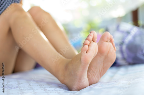 Young female sleeping in bed at home with focus on legs. Feet of woman lying on bed