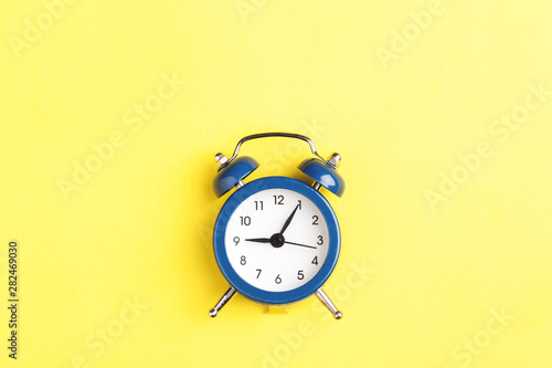 Alarm clock on yellow background.