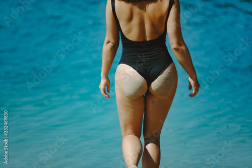 woman in black swimsuit at sand beach view from behind © phpetrunina14